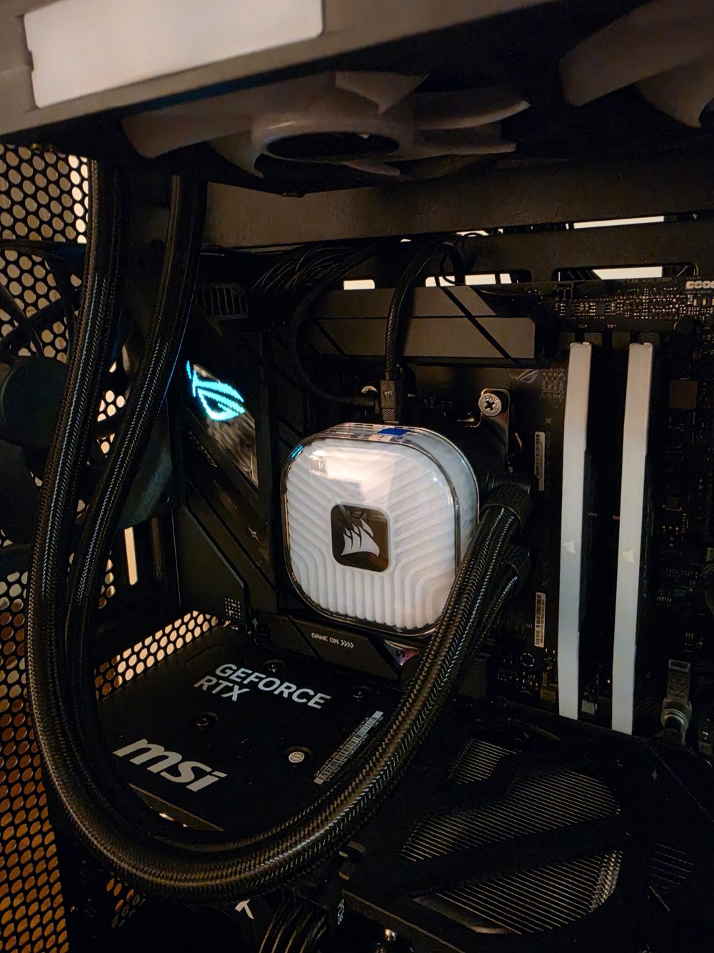 Close-up of a Corsair liquid cooler pump head and braided tubing in a custom PC
